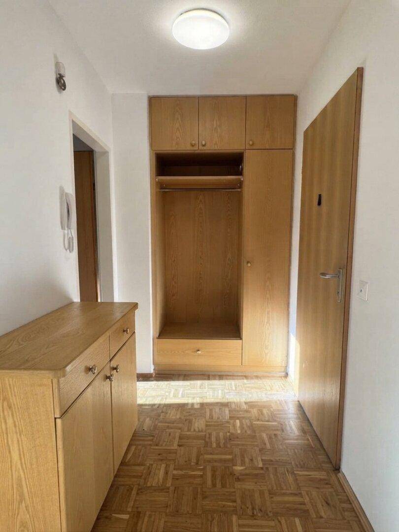 Eingangsbereich mit Parkettboden, Einbauschrank und Garderobenlösung aus Holz.