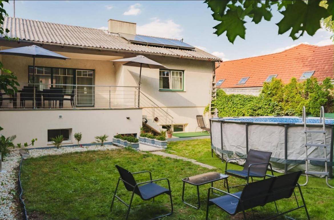 Großer Garten mit Rasenfläche, Aufstellpool und Terrasse, umgeben von viel Grün.