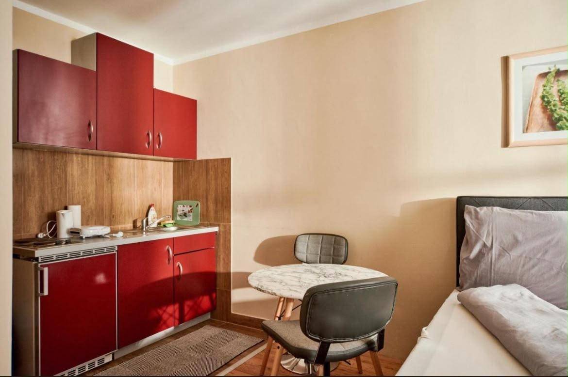 Gemütliches Studio-Apartment mit integrierter Küchenzeile und Essbereich in warmen Farbtönen.