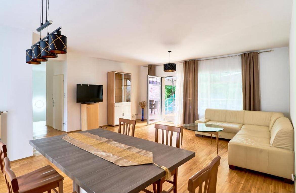 Geräumiger Wohn-Essbereich mit Holzboden, Esstisch und Zugang zum Balkon.