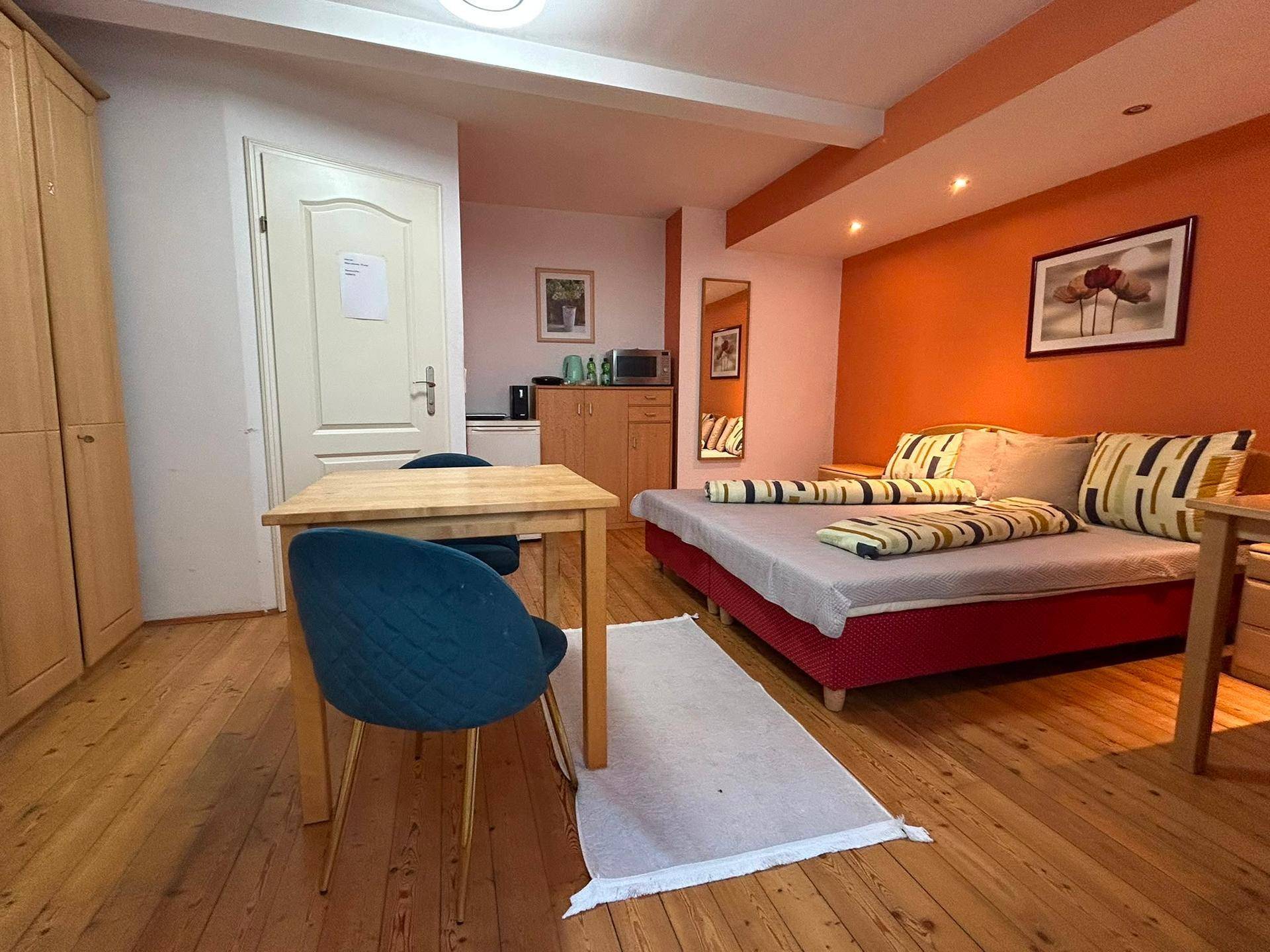 Geräumiges Studio-Apartment mit Doppelbett, Essbereich und kleiner Küchenzeile.
