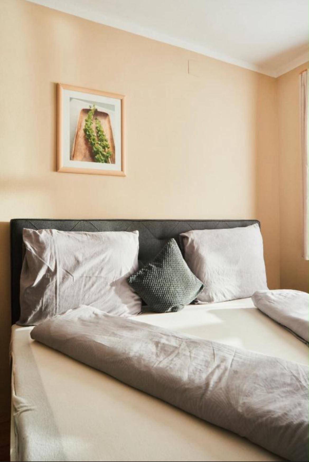 Gemütliches Schlafzimmer mit Doppelbett, hellen Wänden und einem modernen Bild über dem Bett.