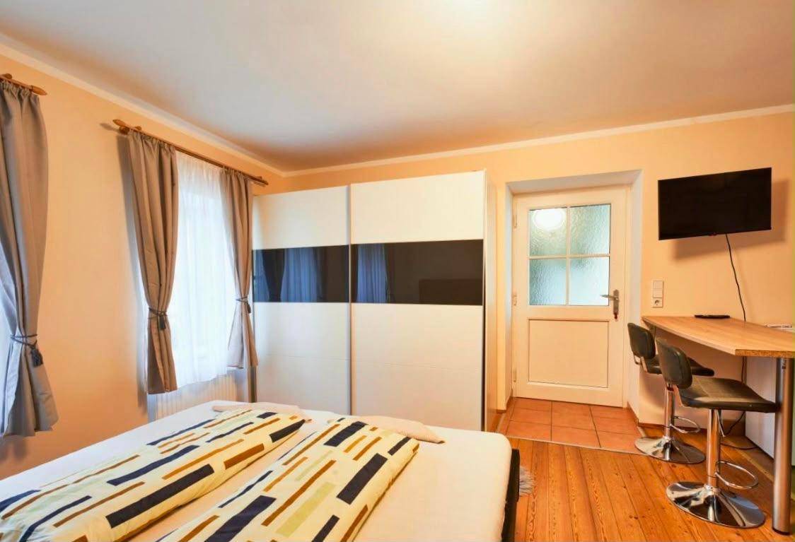 Schlafzimmer mit Doppelbett, Schiebetürenschrank und Blick auf eine kleine Küchenzeile.