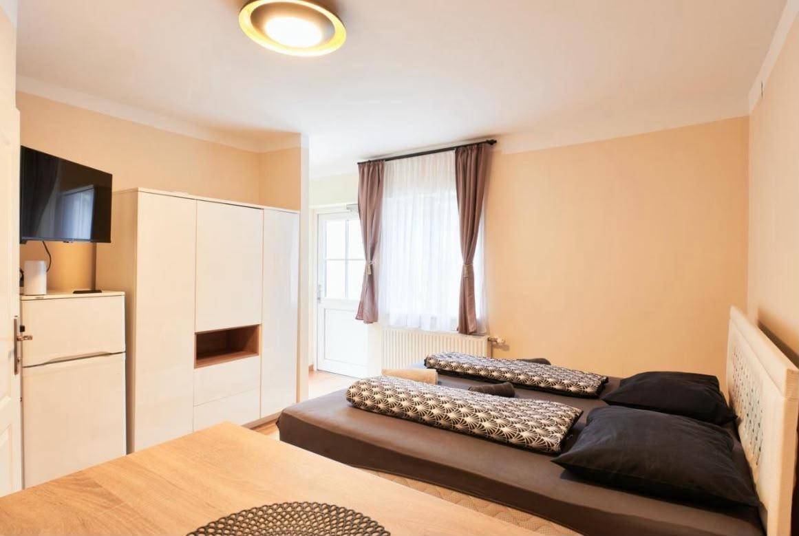 Helles Schlafzimmer mit Doppelbett, Kleiderschrank und Zugang zu einem Außenbereich.