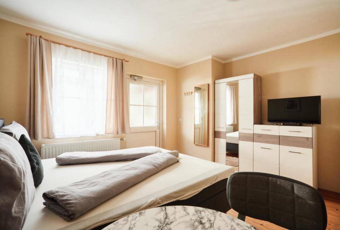 Helles Schlafzimmer mit Doppelbett, Kleiderschrank und Zugang zu einem Außenbereich.