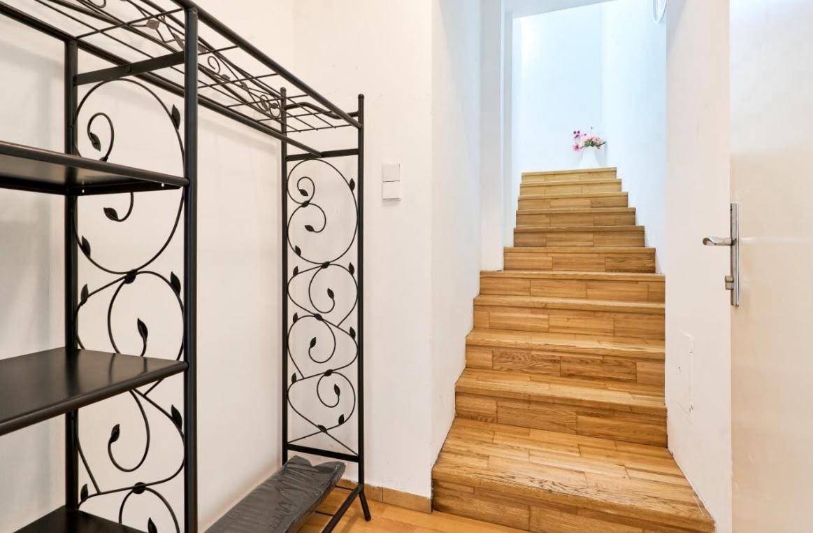 Flur mit Holztreppe und dekorativem Regal, das zum oberen Stockwerk führt.