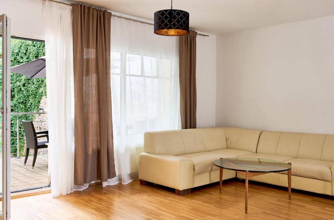 Gemütliches Wohnzimmer mit Sofa, Holzboden und direktem Zugang zur Terrasse.
