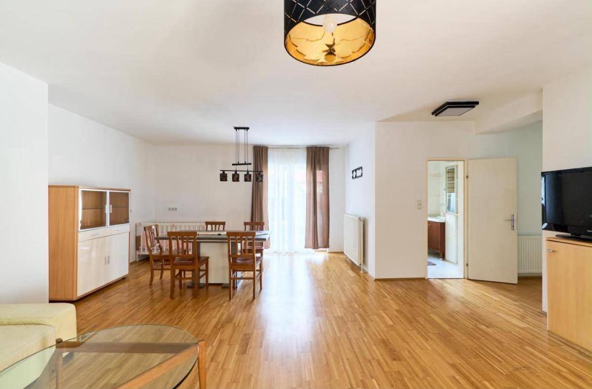 Geräumiger Wohn-Essbereich mit Holzboden, Esstisch und Zugang zum Balkon.