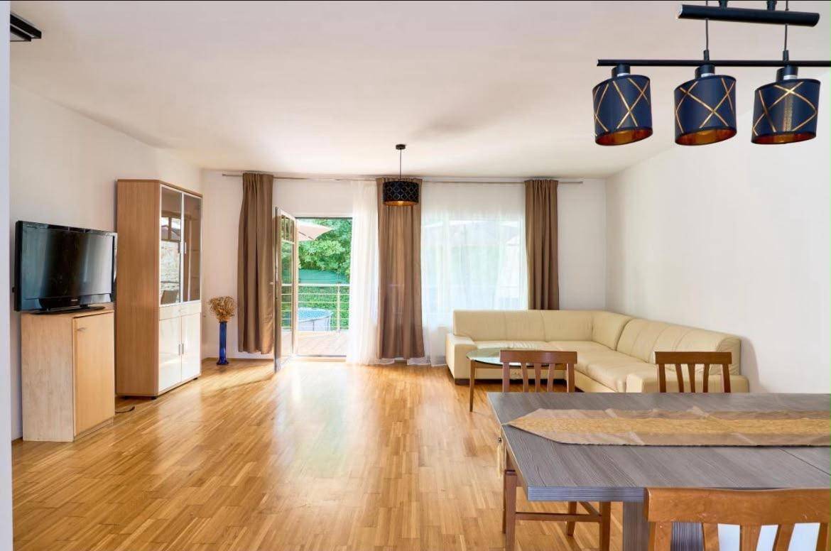 Heller Wohn- und Essbereich mit Holzboden und Zugang zum Balkon.