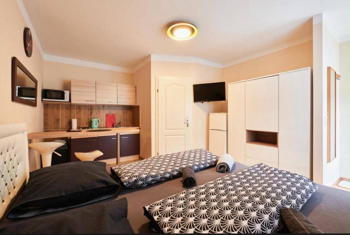 Modernes Studio-Apartment mit Küchenzeile, Doppelbett und Essbereich auf Fliesenboden.