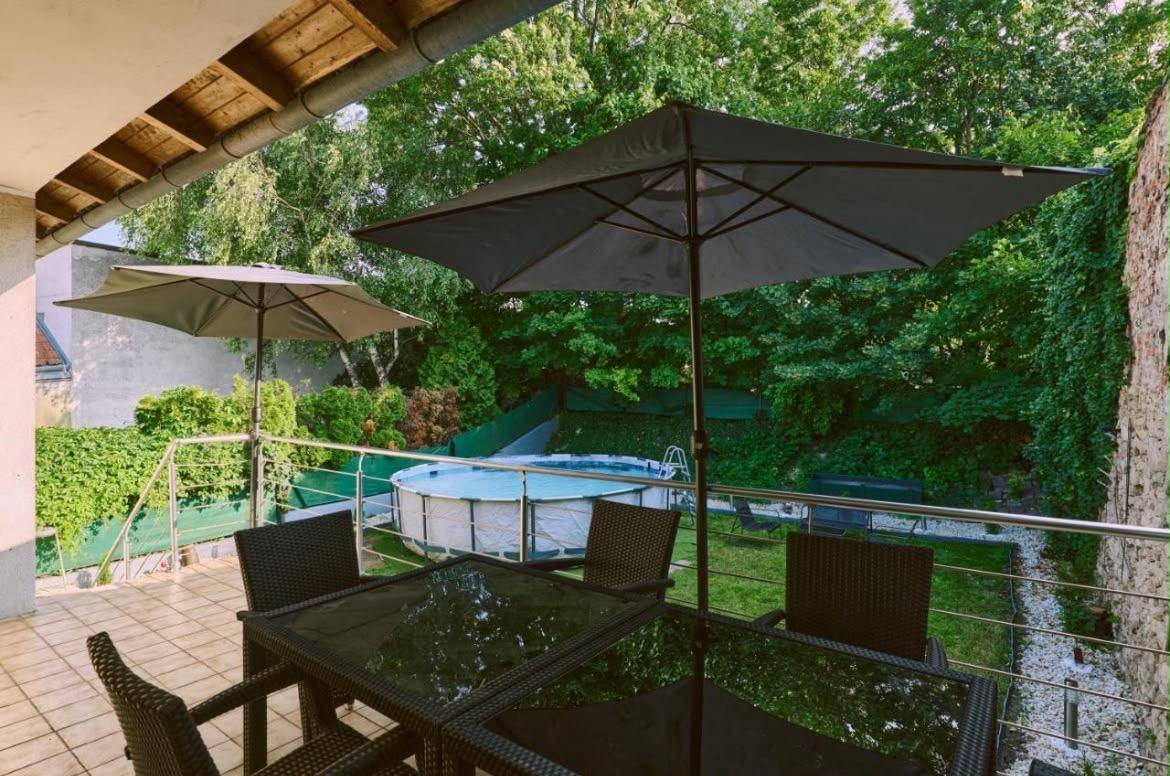Balkon mit Sitzgelegenheiten und Blick auf den Garten mit Pool und Bäumen.