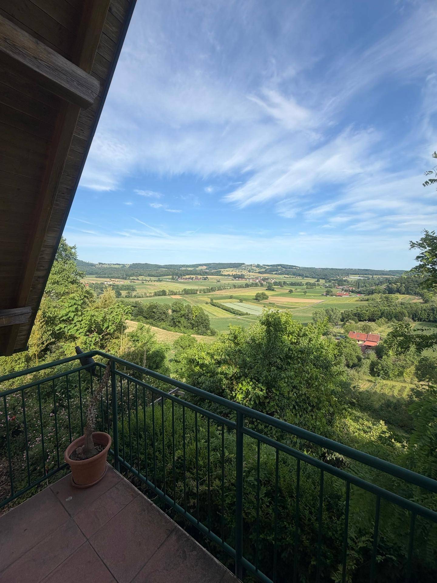 Balkon mit weitem Blick über eine malerische grüne Landschaft und Felder.