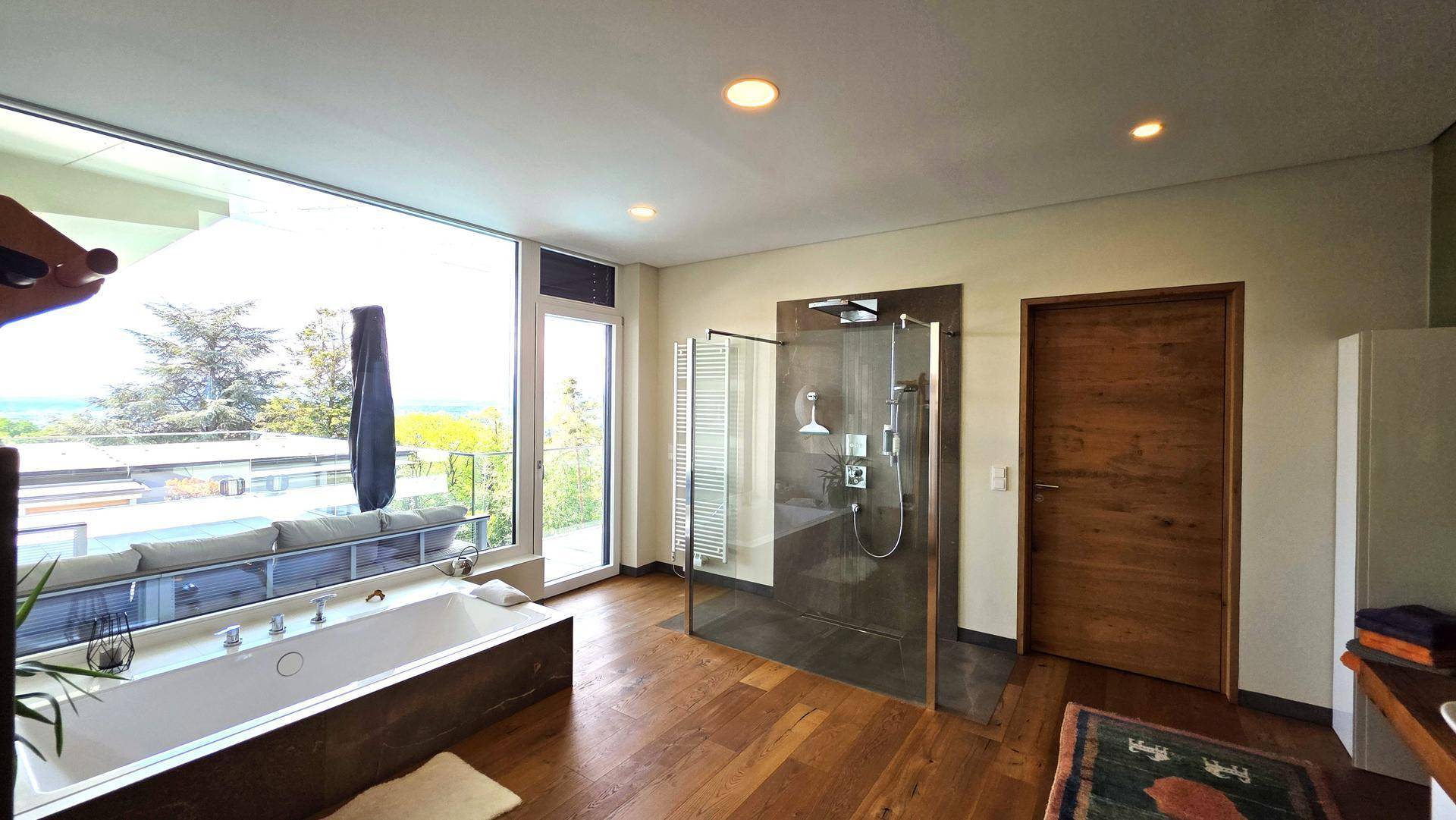 Luxuriöses Badezimmer mit großer Badewanne, begehbarer Dusche und Panoramablick.