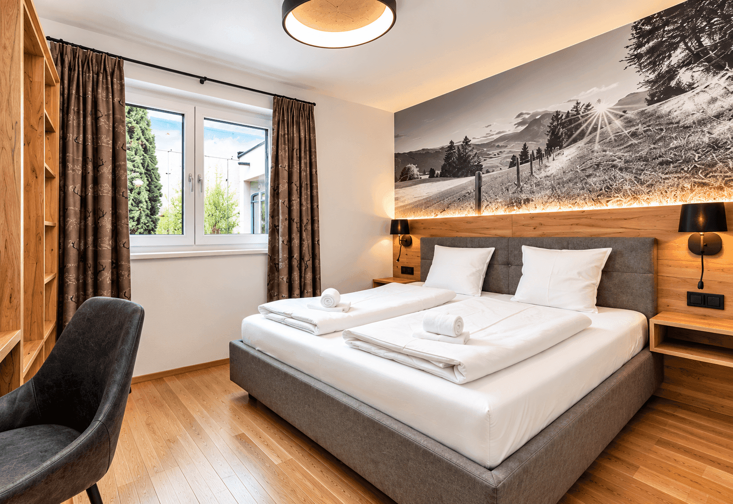 Modernes Schlafzimmer mit Doppelbett, Holzboden und Wandbild mit Naturmotiv.
