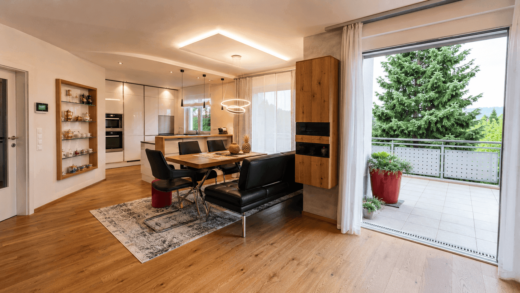 Heller offener Wohn-Essbereich mit moderner Einbauküche, Holzboden und Zugang zu einer Terrasse mit Weitblick.
