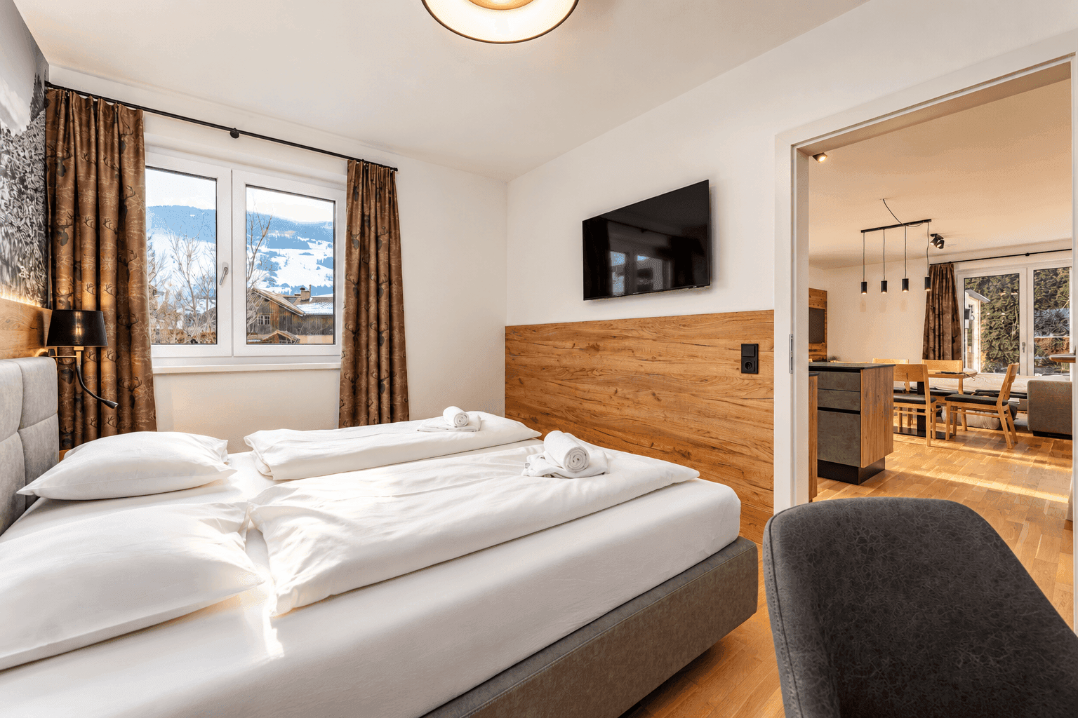 Schlafzimmer mit Doppelbett und Blick in den offenen Wohn-Essbereich.