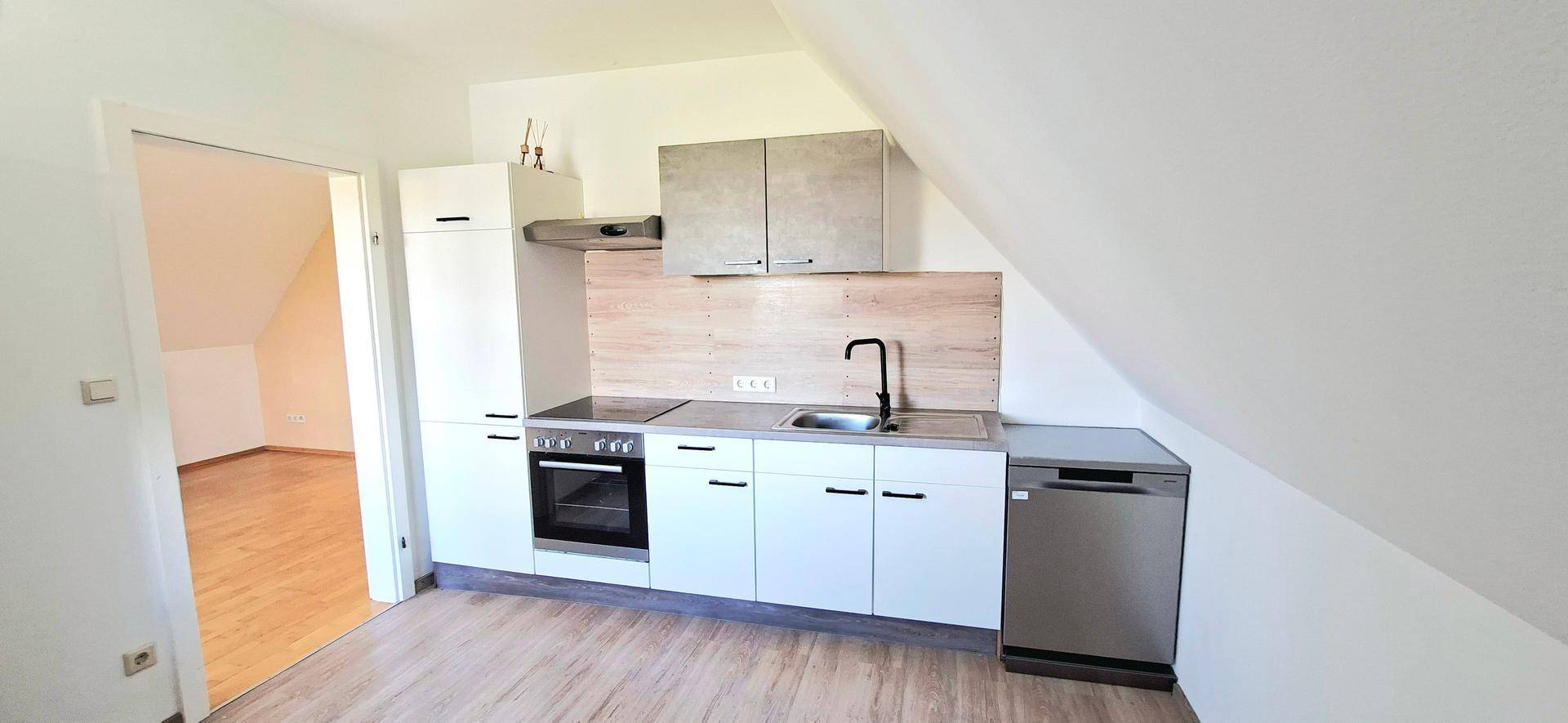 Moderne Küchenzeile im Dachgeschoss mit weißen Schränken und integriertem Geschirrspüler.