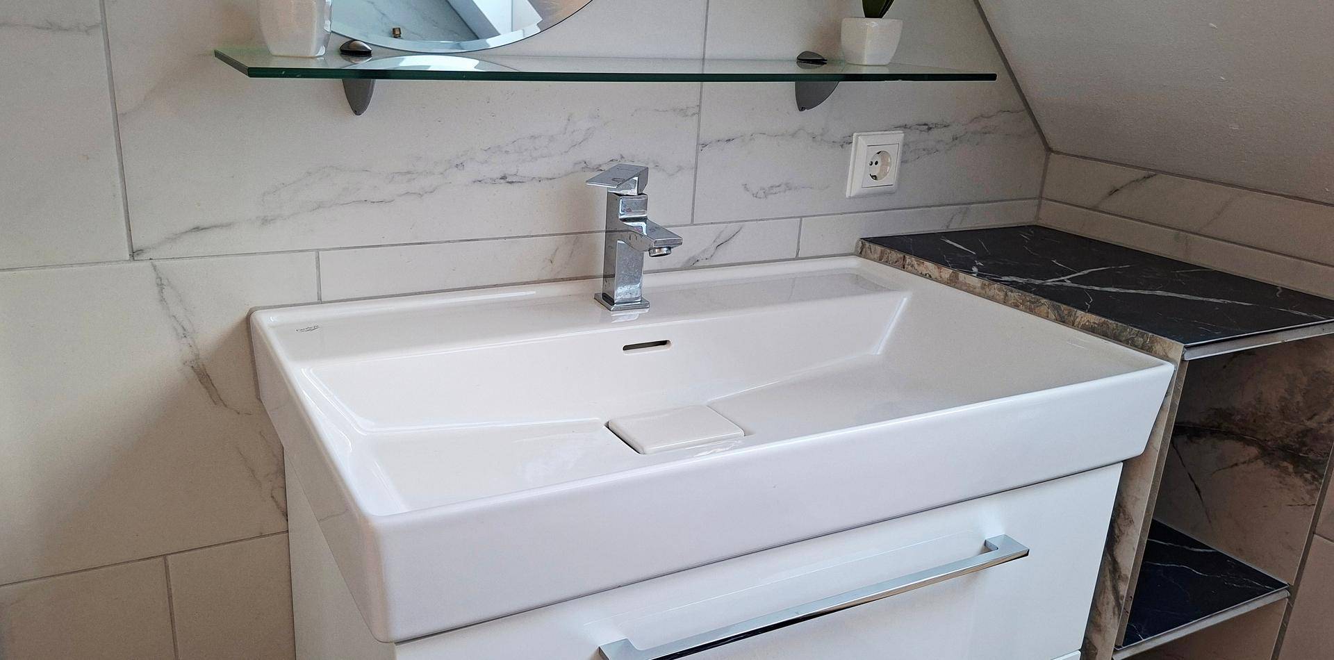 Detailansicht eines modernen Waschbeckens mit Armatur und Ablagefläche.