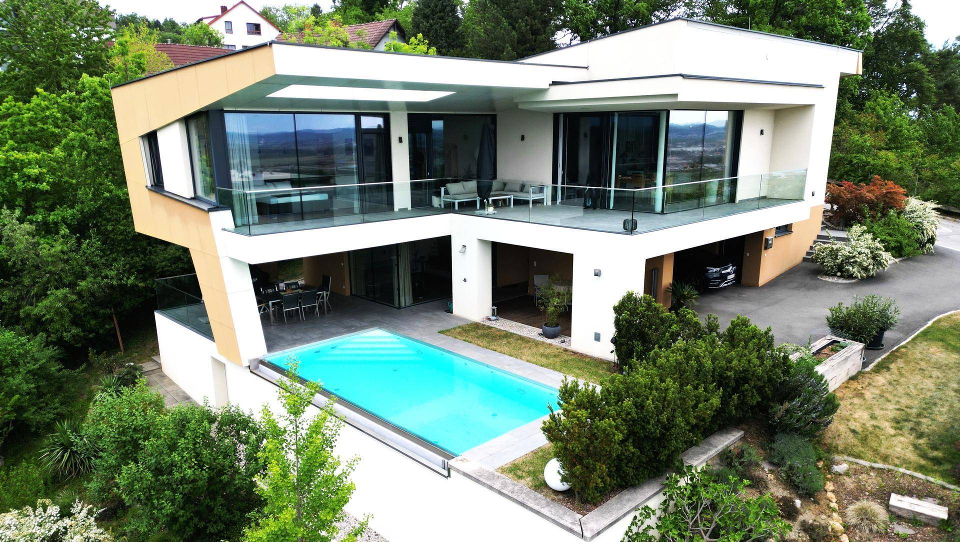 Panoramablick von oben auf die moderne Villa mit Pool, Terrassen und weitläufiger Auffahrt.