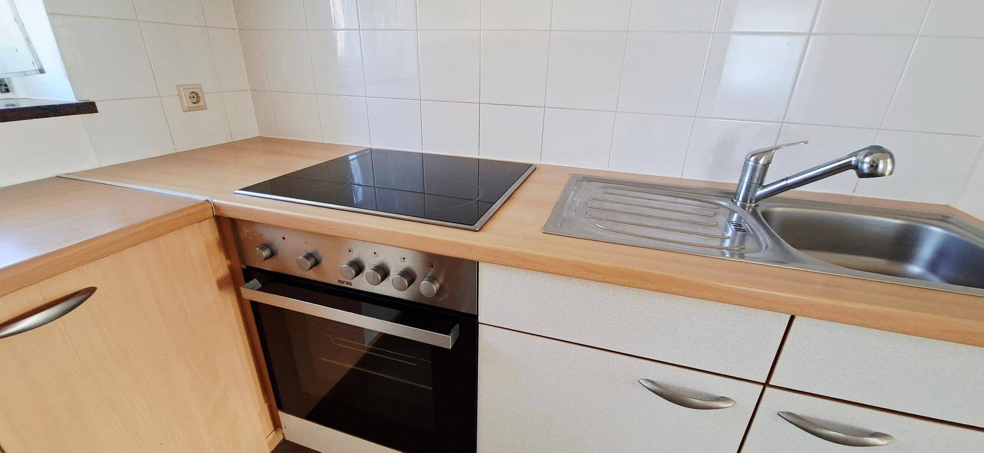 Detailansicht der Küchenzeile mit Induktionskochfeld, Spüle und Holz-Arbeitsplatte.
