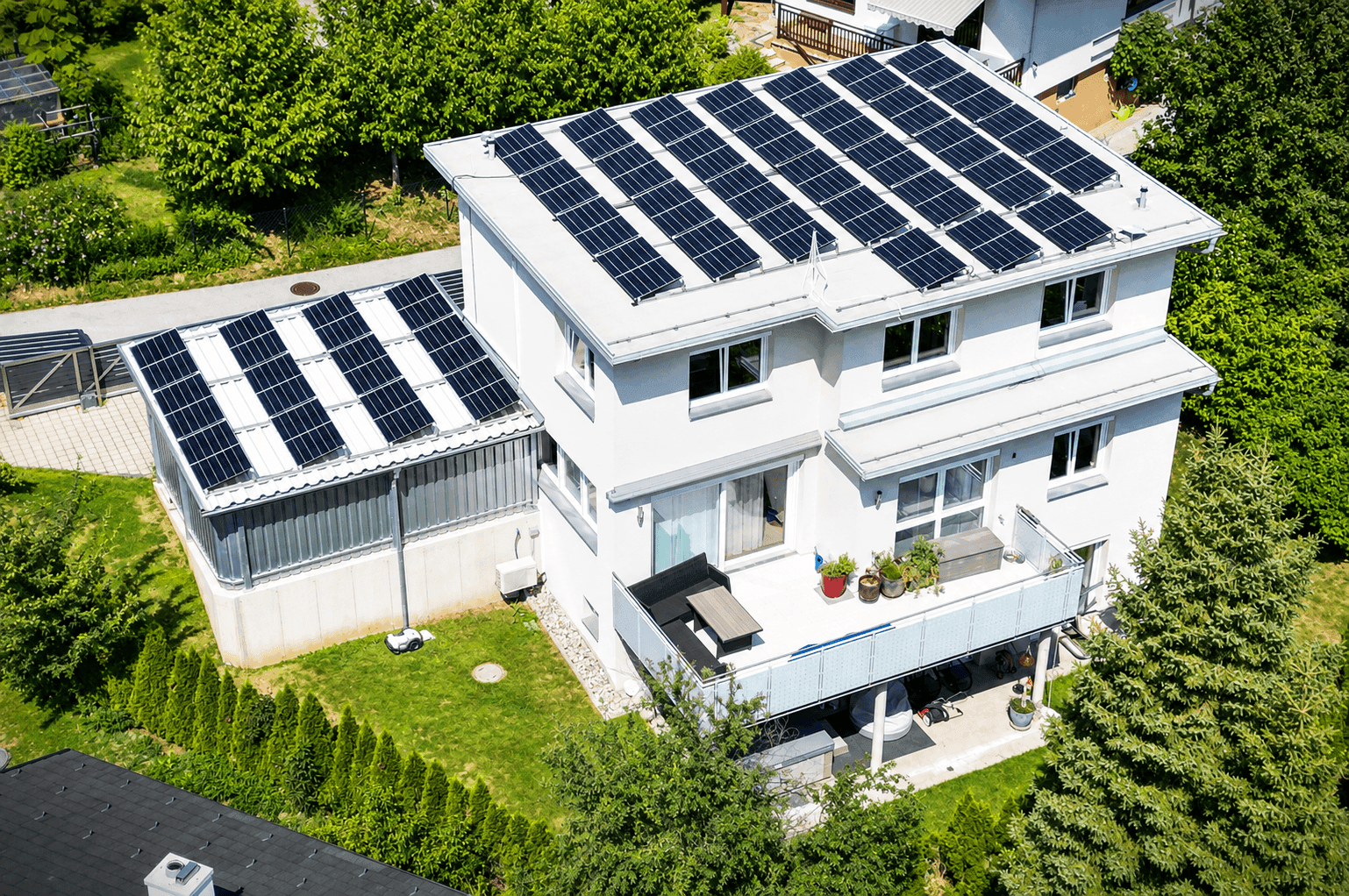 Modernes Einfamilienhaus mit umfangreicher Photovoltaikanlage auf dem Dach und grüner Umgebung.
