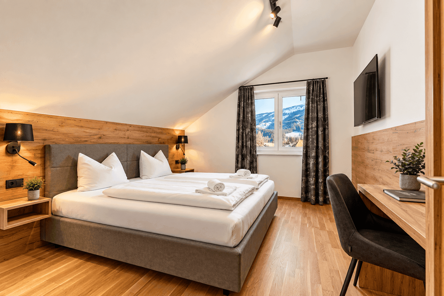 Gemütliches Schlafzimmer im Dachgeschoss mit Holzakzenten, Doppelbett und Bergblick.