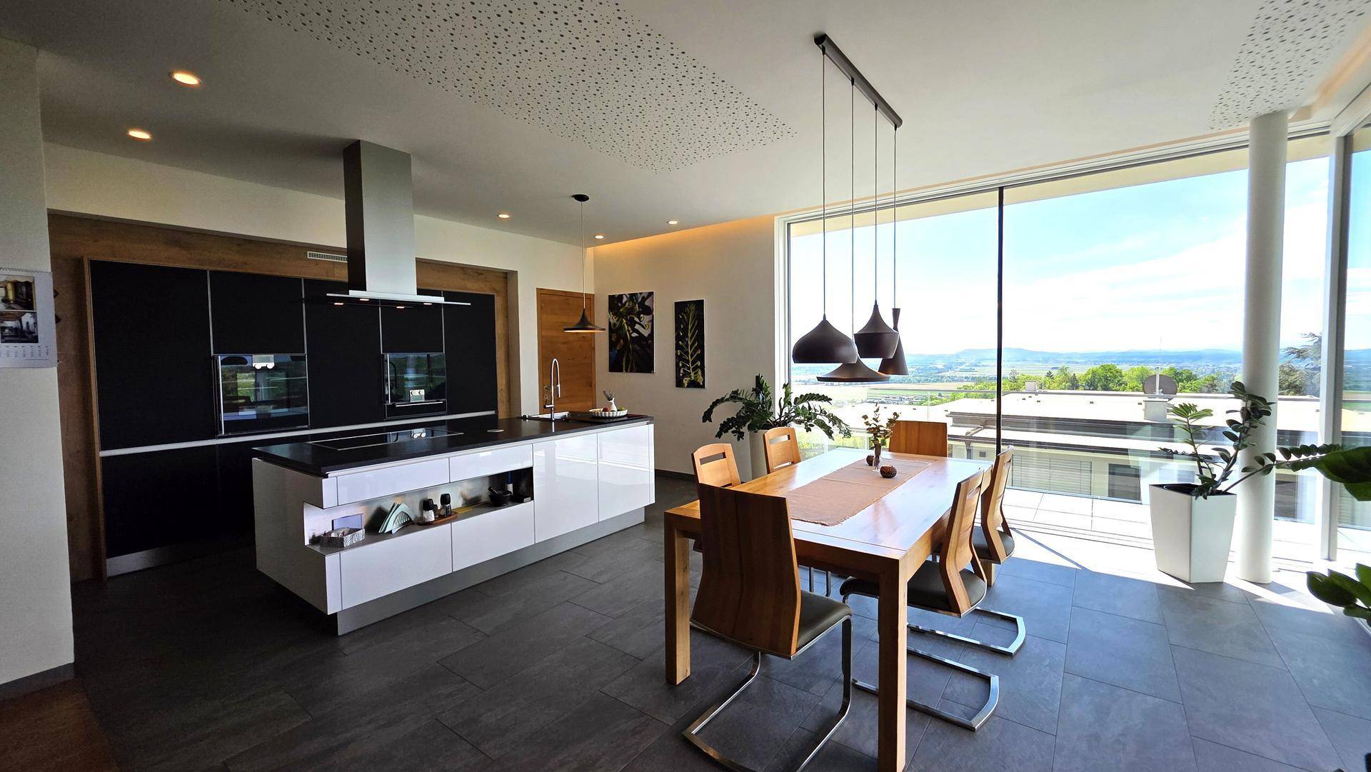 Moderne offene Küche mit Essbereich und raumhohen Fenstern mit weitem Ausblick.