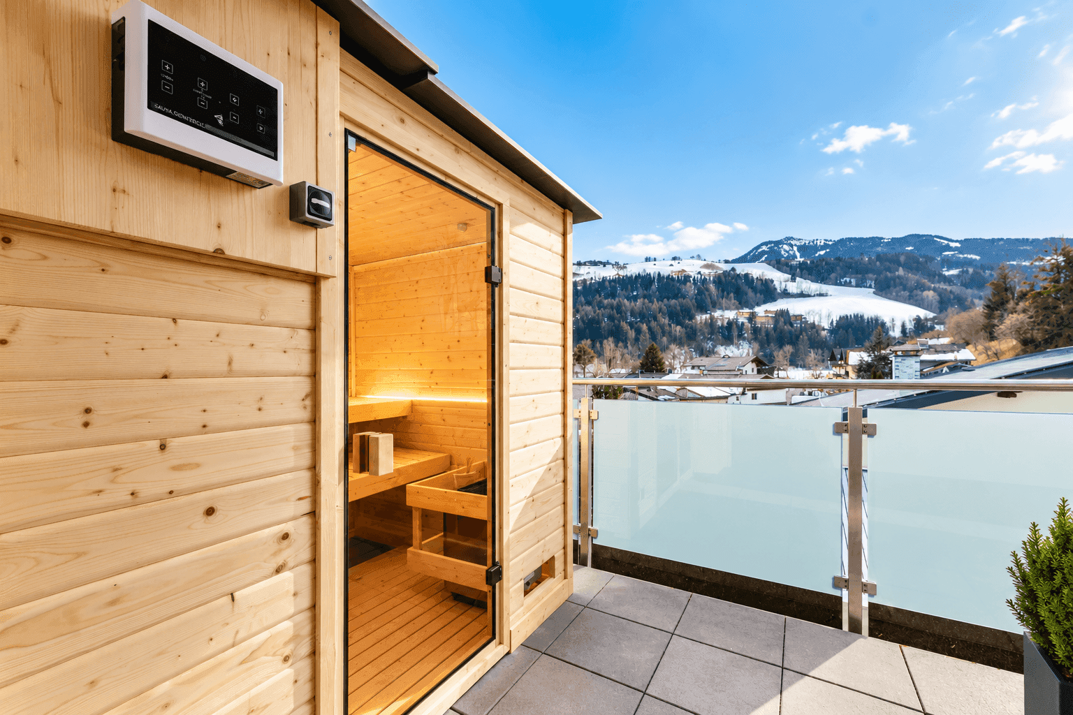 Externe Sauna auf einer Terrasse mit Panoramablick auf die verschneiten Berge.