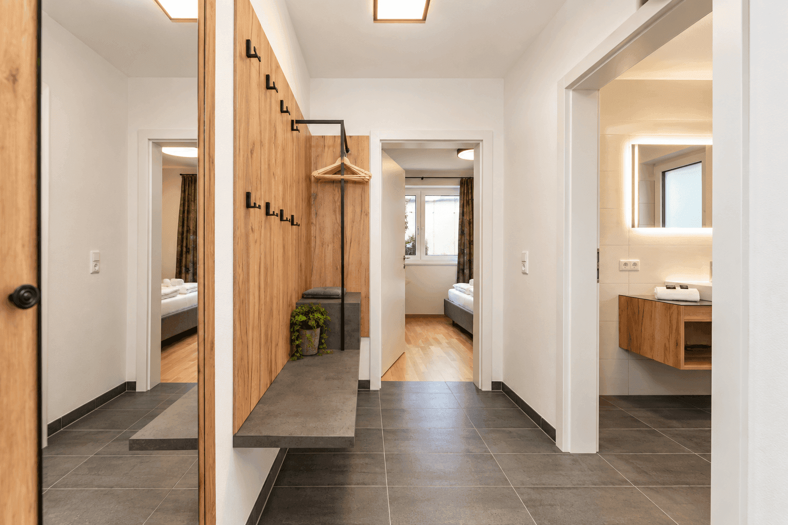 Moderner Flur mit Garderobe, Spiegel und Zugang zu Bad und Schlafzimmer.