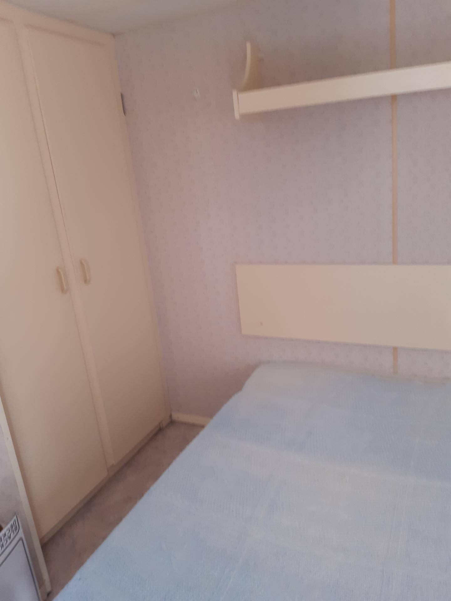 Schlafzimmer mit Bett und integriertem Kleiderschrank in einfacher Ausführung.