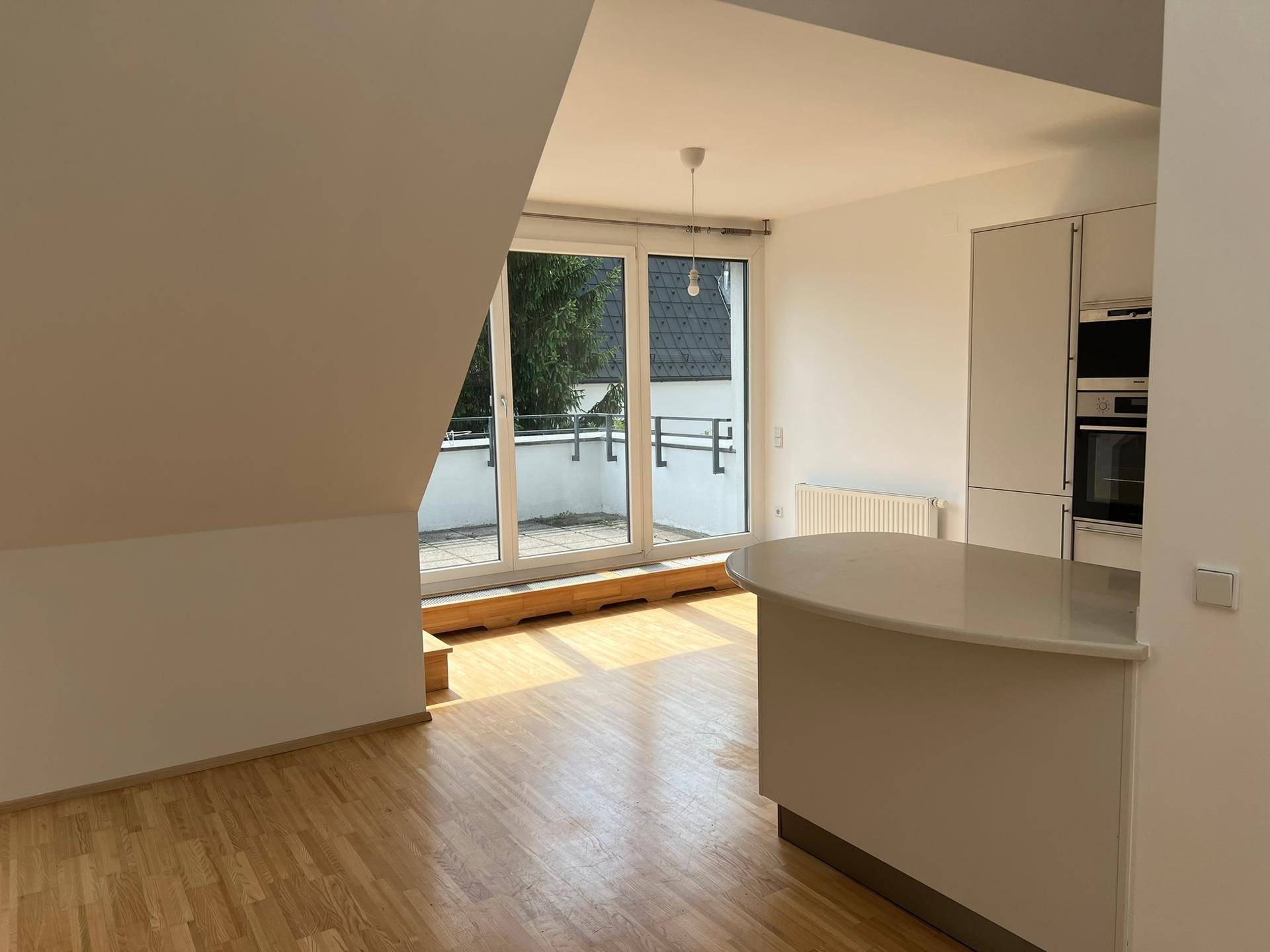 Offener Wohnbereich mit Küchenzeile, Holzboden und Zugang zur sonnigen Terrasse.