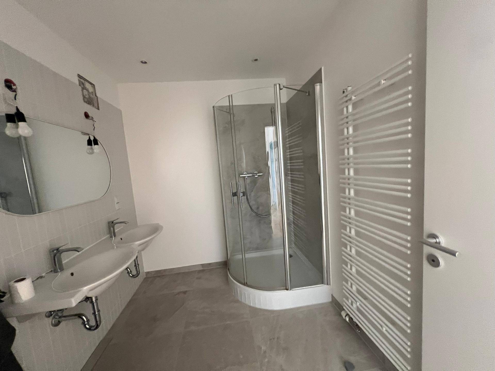 Modernes Badezimmer mit Doppelwaschbecken, Duschkabine und einem praktischen Handtuchheizkörper.