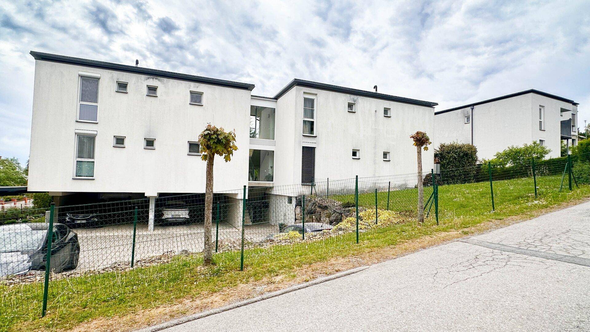 Moderne weiße Gebäude mit Flachdächern und integrierten Parkplätzen in ländlicher Umgebung.