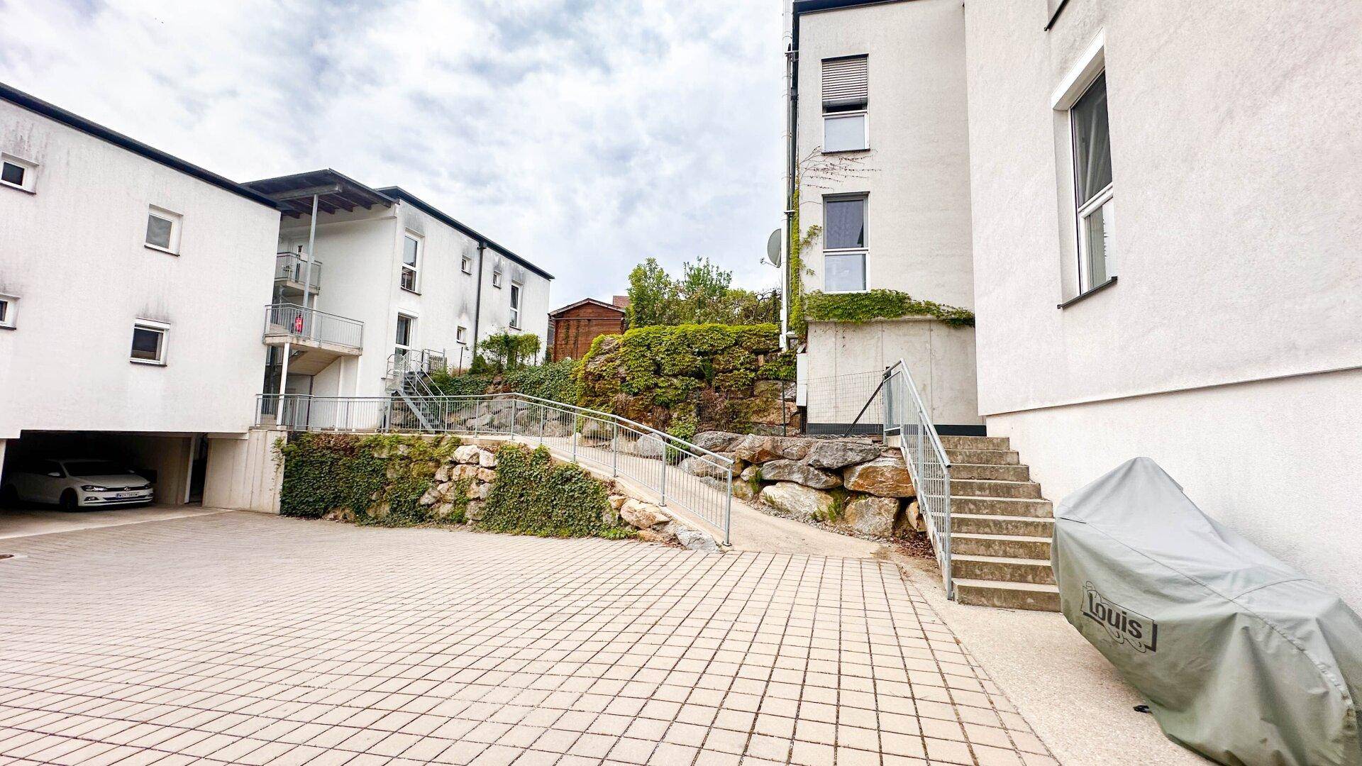 Außenbereich mit gepflastertem Weg, Rampe und Treppe zu den Eingängen der Wohngebäude.
