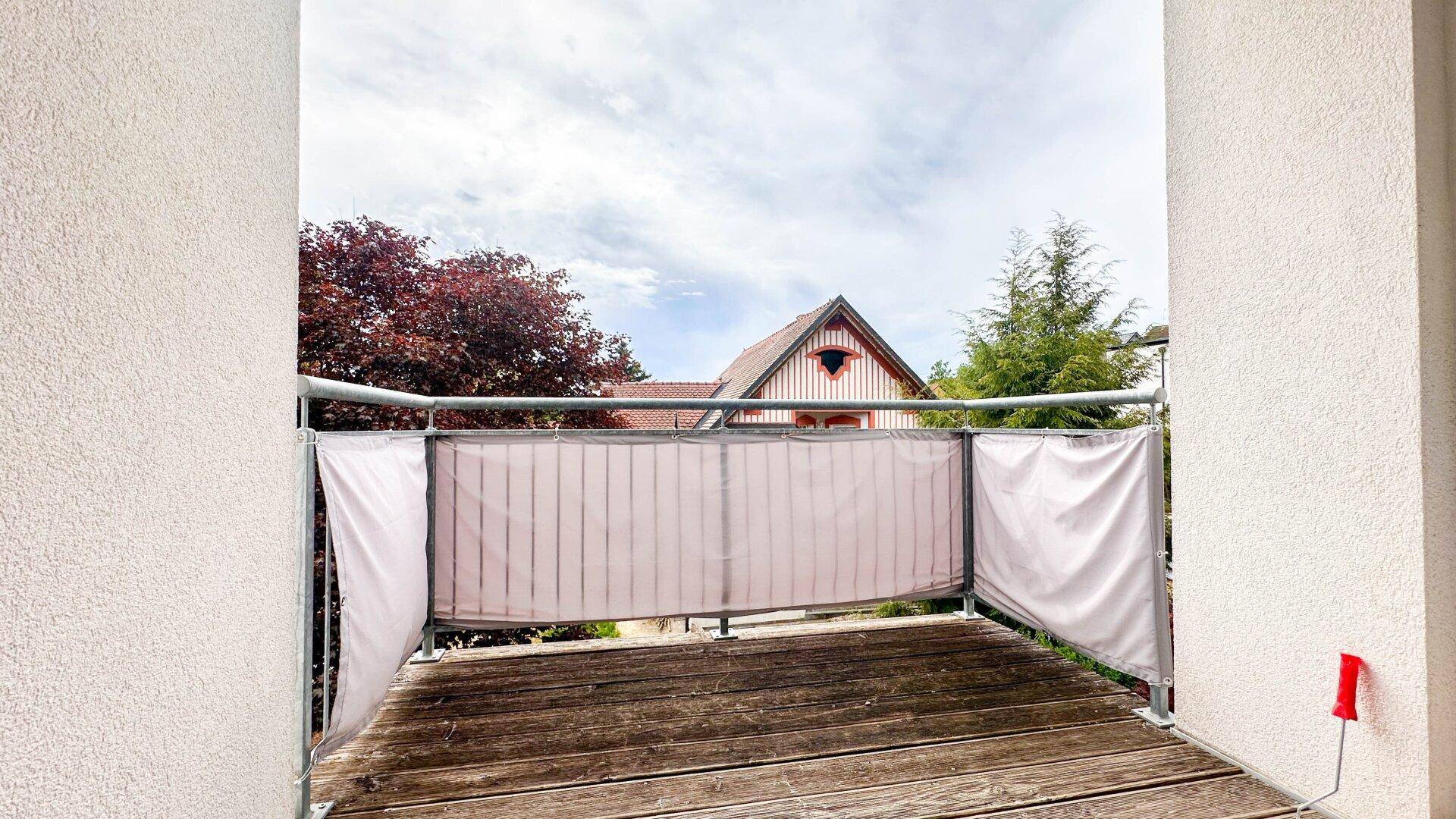 Kleiner Balkon mit Holzboden und Sichtschutz, ideal für entspannte Stunden im Freien.