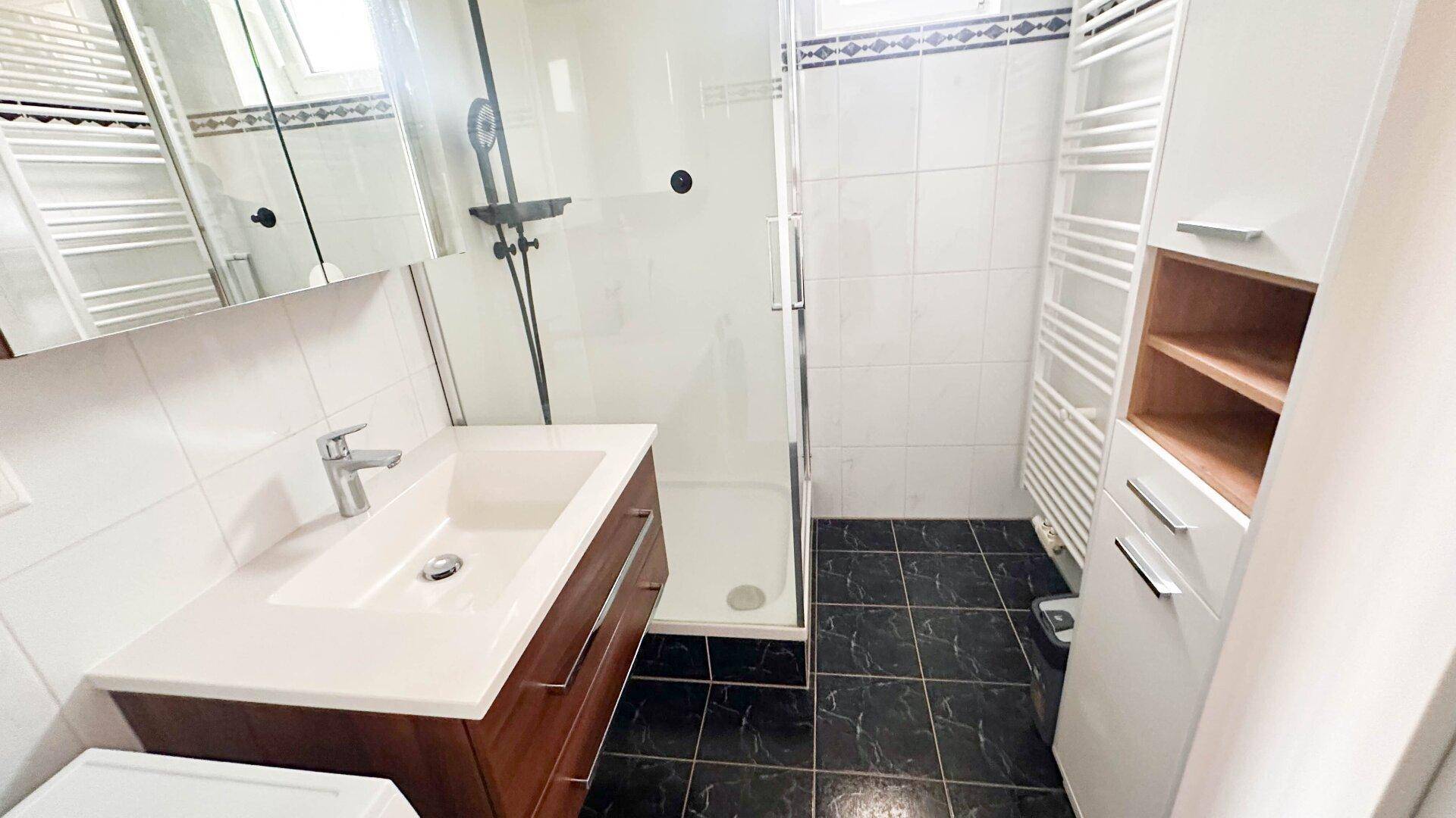 Modernes Badezimmer mit Duschbereich, Waschbecken und praktischem Spiegelschrank.