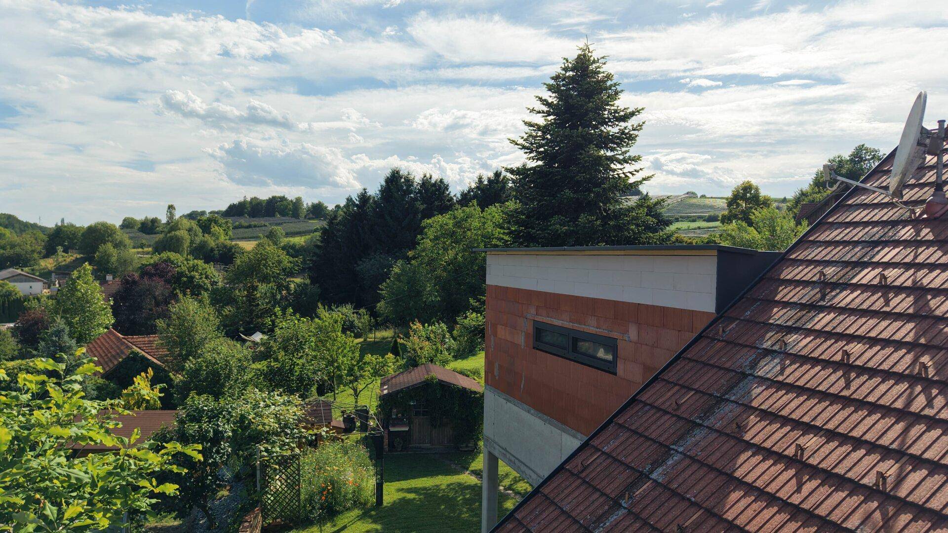 Ausblick über die Dächer der Nachbarschaft und die umliegende grüne Hügellandschaft.