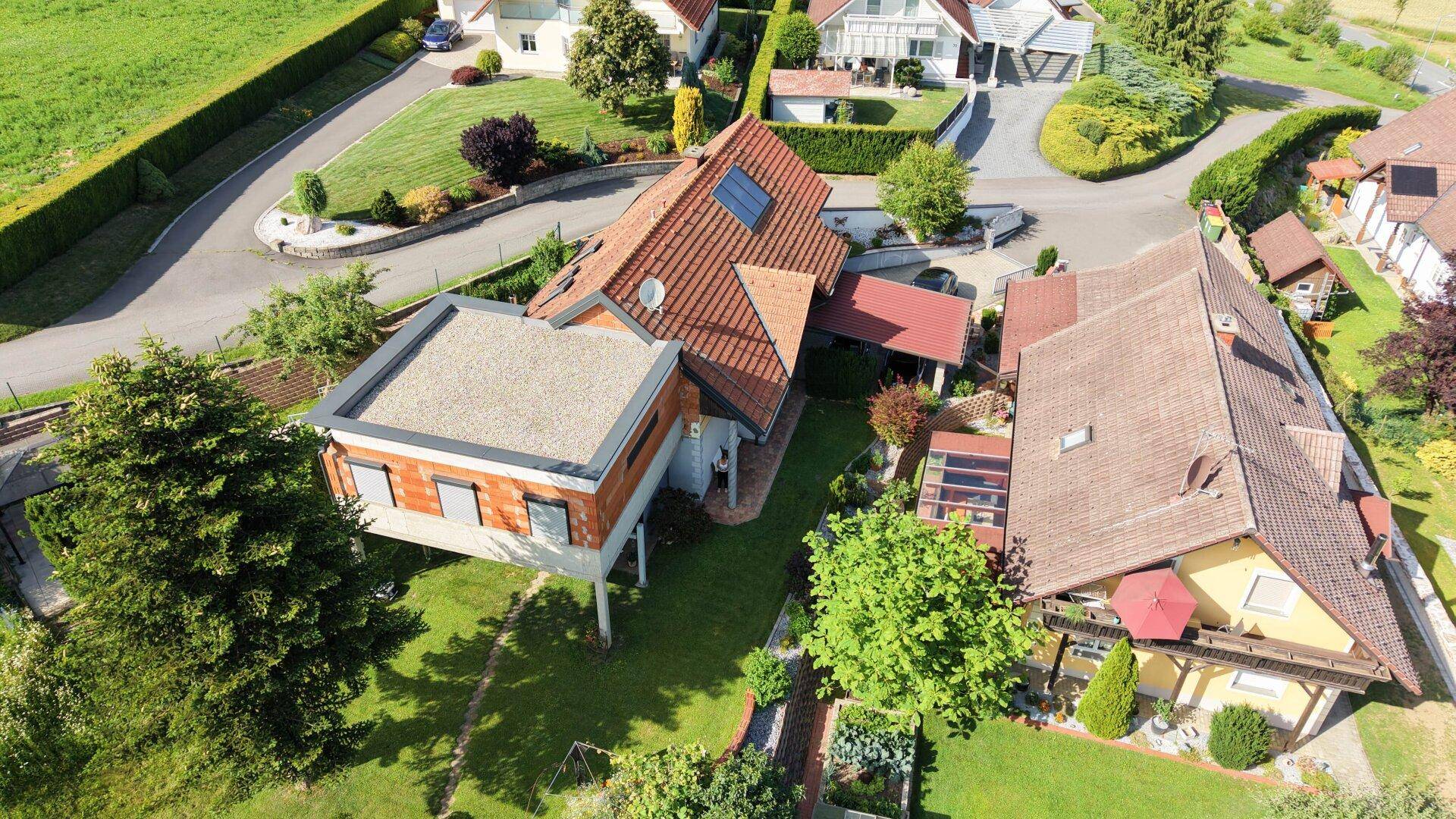 Vogelperspektive eines Wohnhauses mit moderner Erweiterung und traditionellem Ziegeldach.