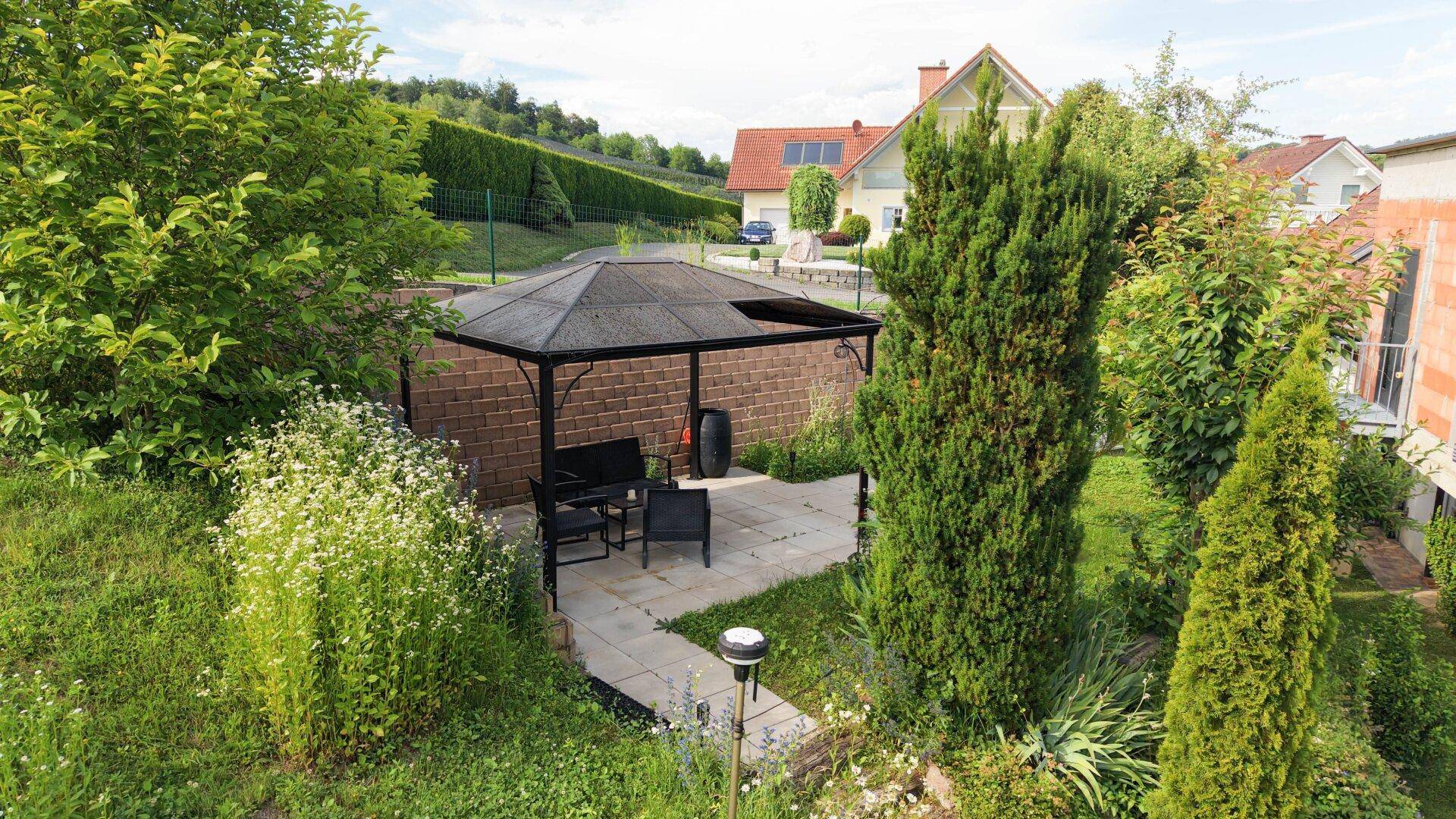 Gemütlicher Außenbereich mit gepflasterter Terrasse, Gartenmöbeln und einem Pavillon.