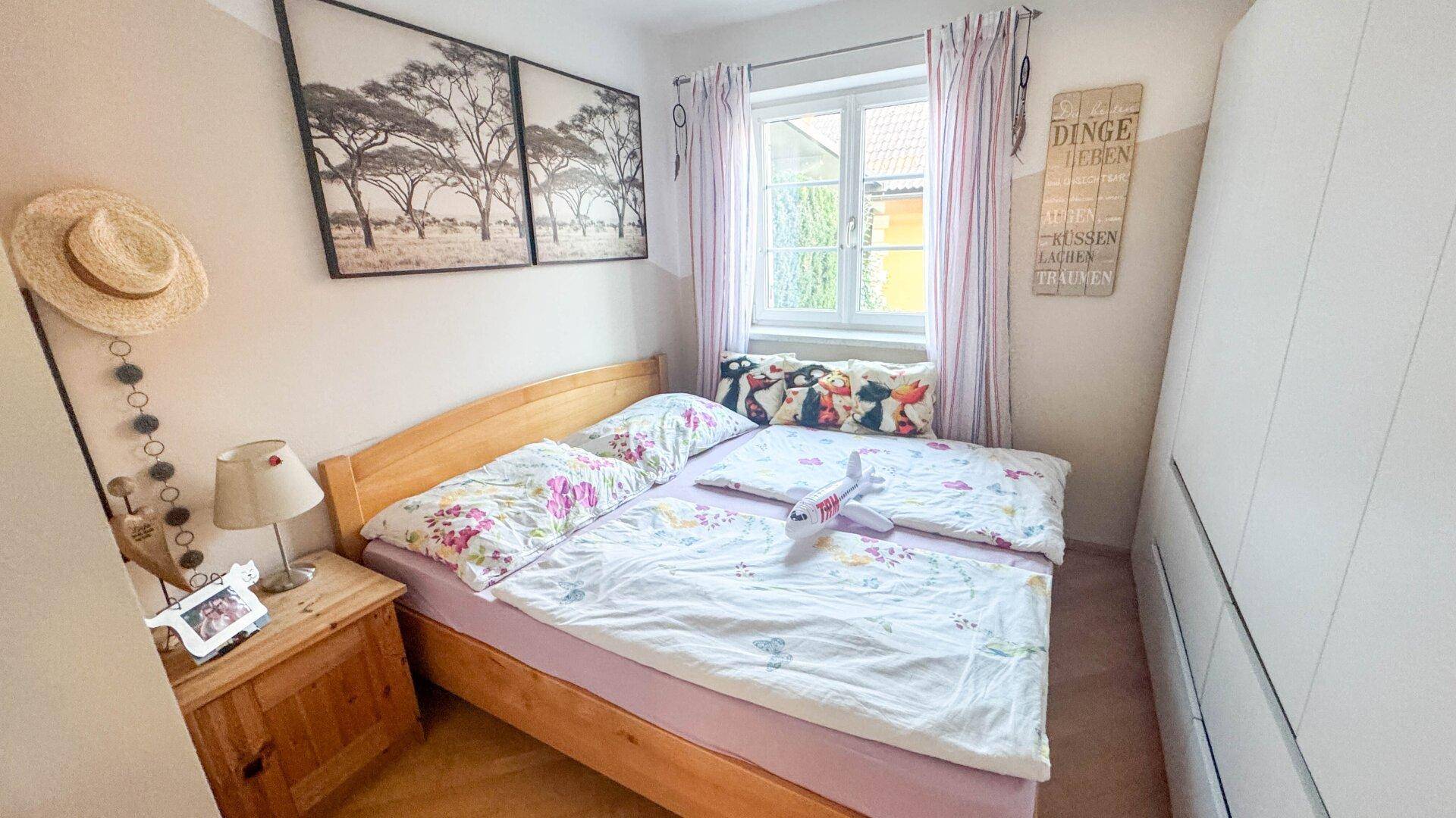 Gemütliches Schlafzimmer mit Doppelbett, Holzmöbeln und Fenster mit Vorhängen.