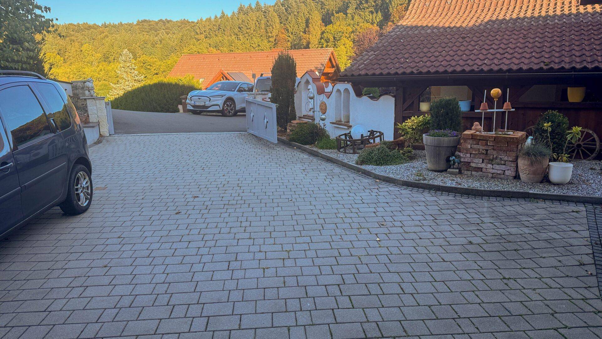 Gepflasterter Vorplatz mit Parkmöglichkeiten und dekorativen Elementen am Haus.