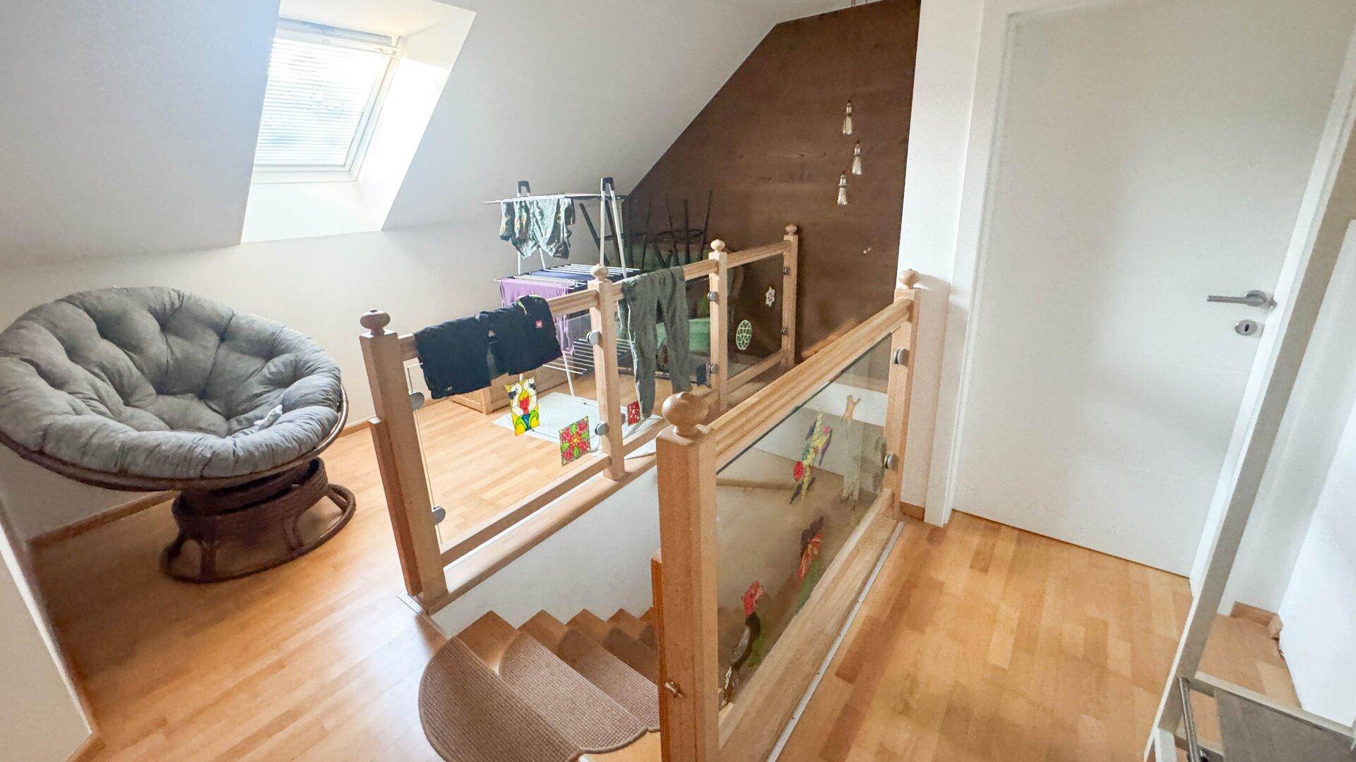 Heller Flur im Obergeschoss mit Holzgeländer, Dachschräge und Dachfenster.