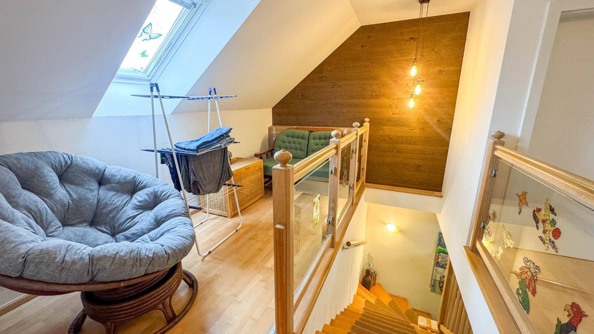 Dachgeschossbereich mit Dachfenster, Holzboden und einer gemütlichen Sitzgelegenheit.