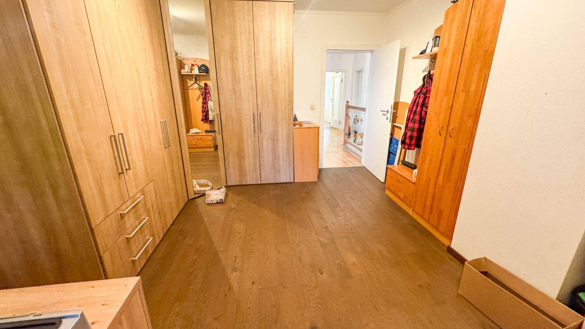 Schlafzimmer oder Ankleidebereich mit Holzschränken und dunklem Holzboden.