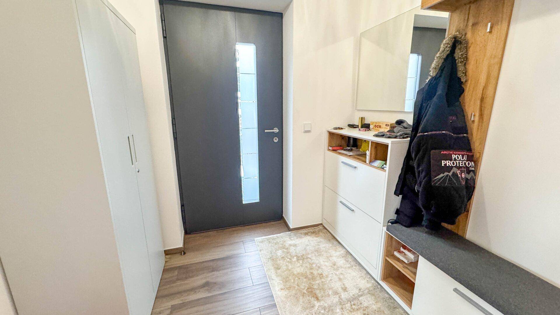 Eingangsbereich mit moderner Haustür, Garderobe und Schuhschrank.