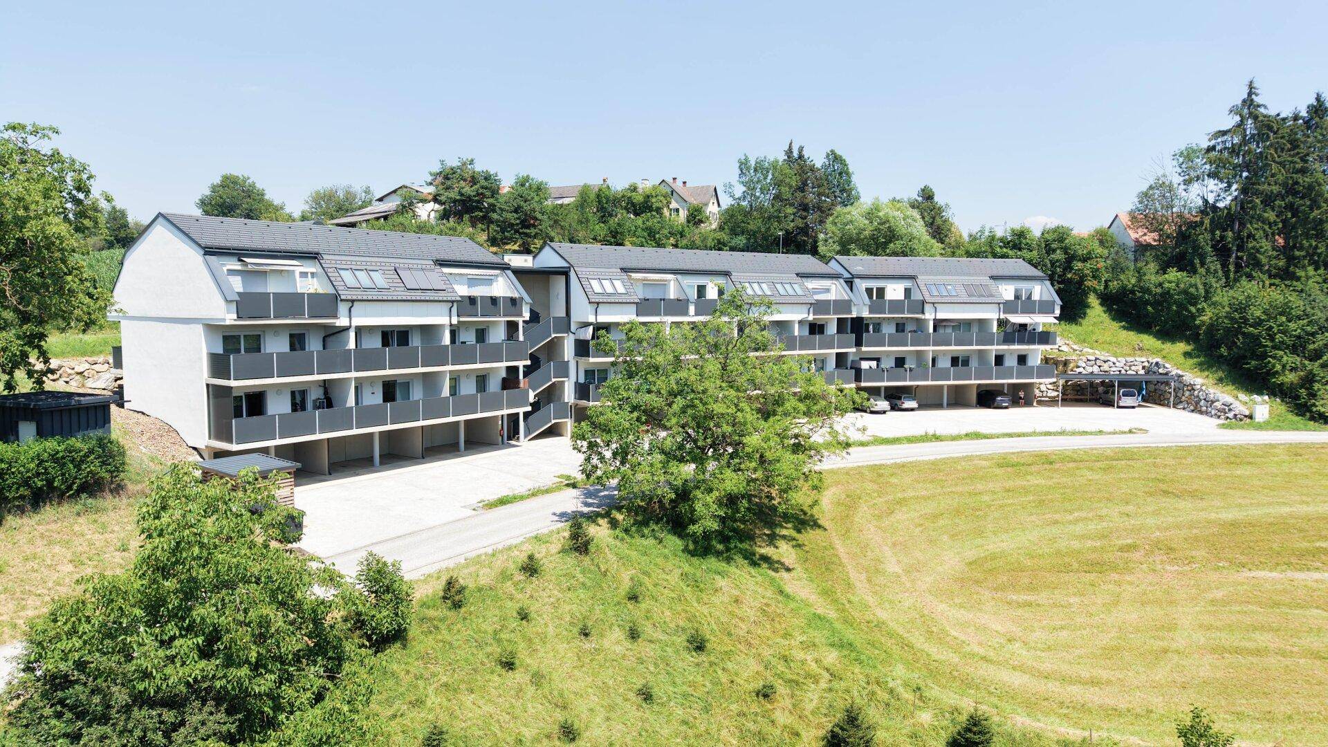 Übersicht der modernen Wohngebäude mit Balkonen und Parkplätzen in einer ländlichen Umgebung.
