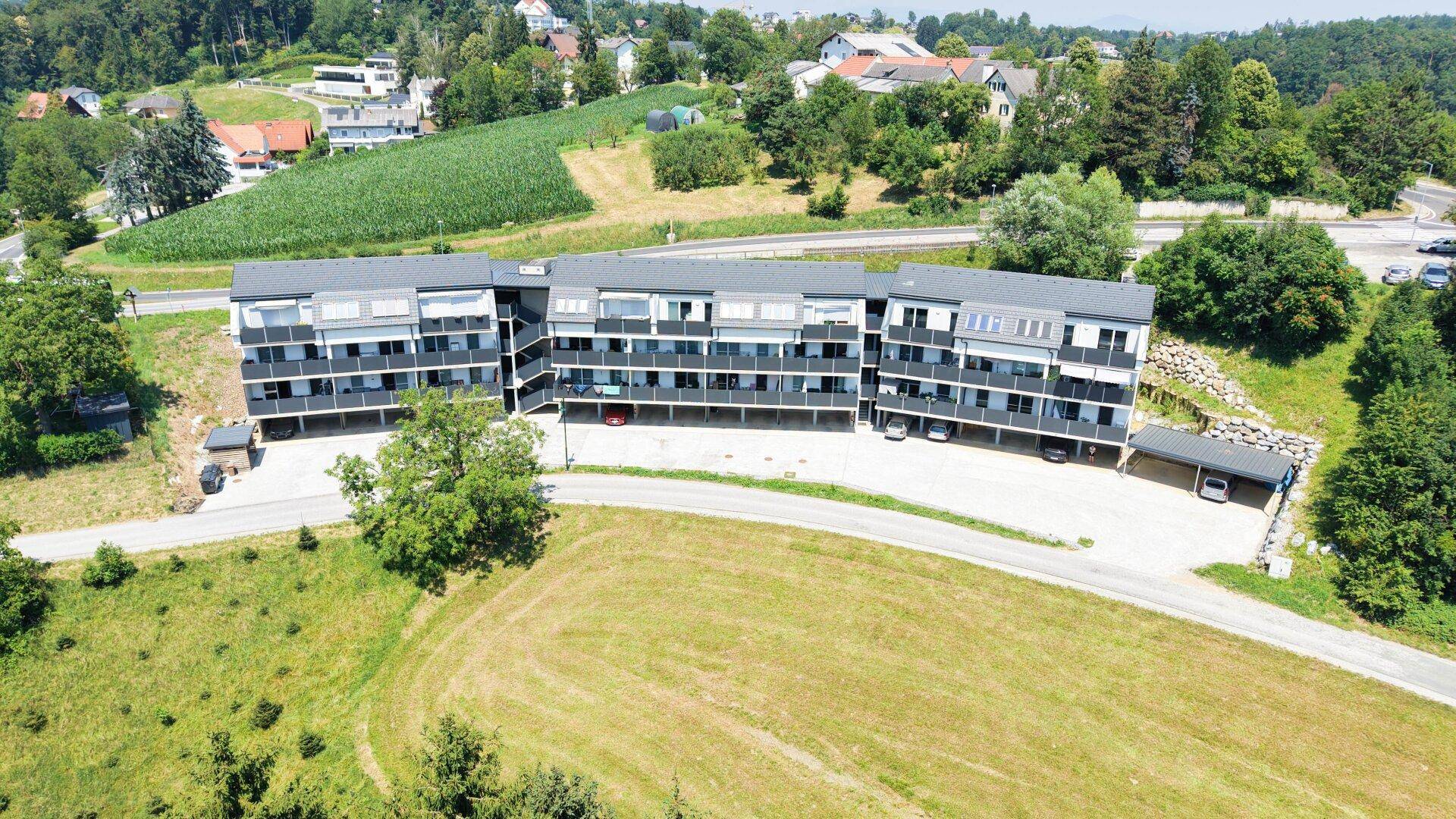 Weitläufige Luftaufnahme der modernen Wohnanlage in einer idyllischen, grünen Landschaft mit Feldern.