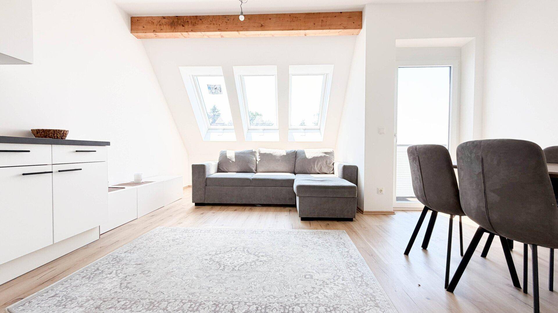 Gemütlicher Wohnbereich mit Sofa, Esstisch und großen Dachfenstern für viel Tageslicht.