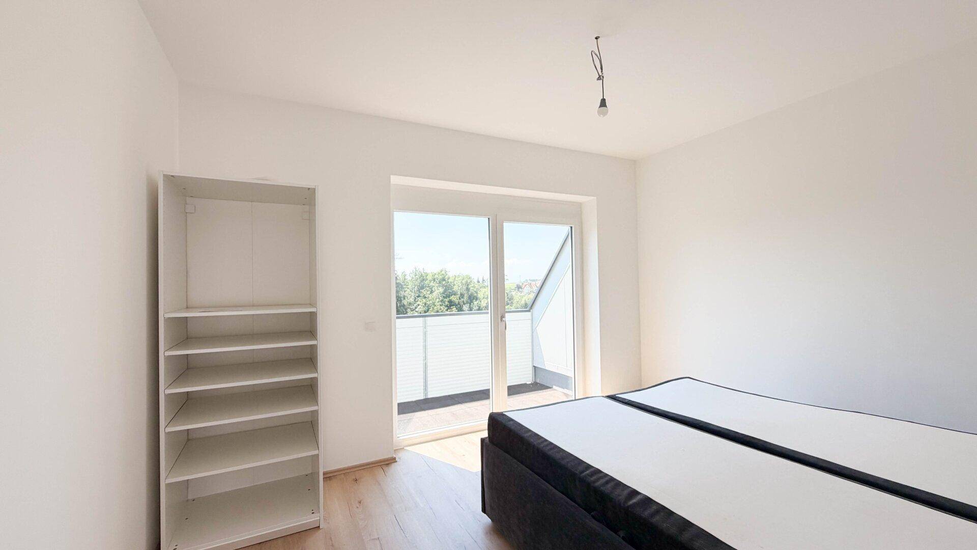 Helles Schlafzimmer mit Zugang zum Balkon und Platz für einen Kleiderschrank.