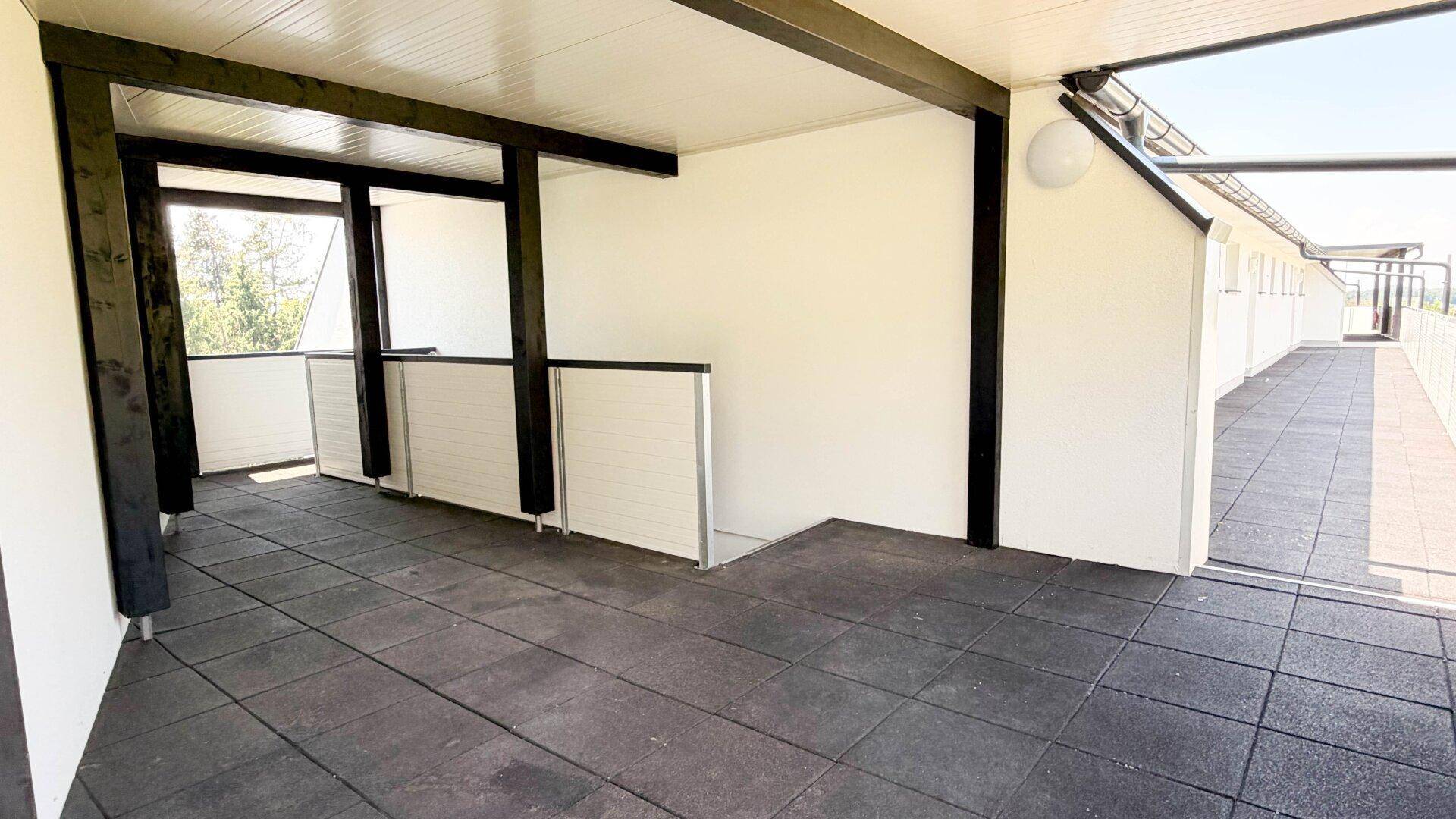 Geräumiger überdachter Loggia-Bereich mit dunklem Fliesenboden und offener Gestaltung.